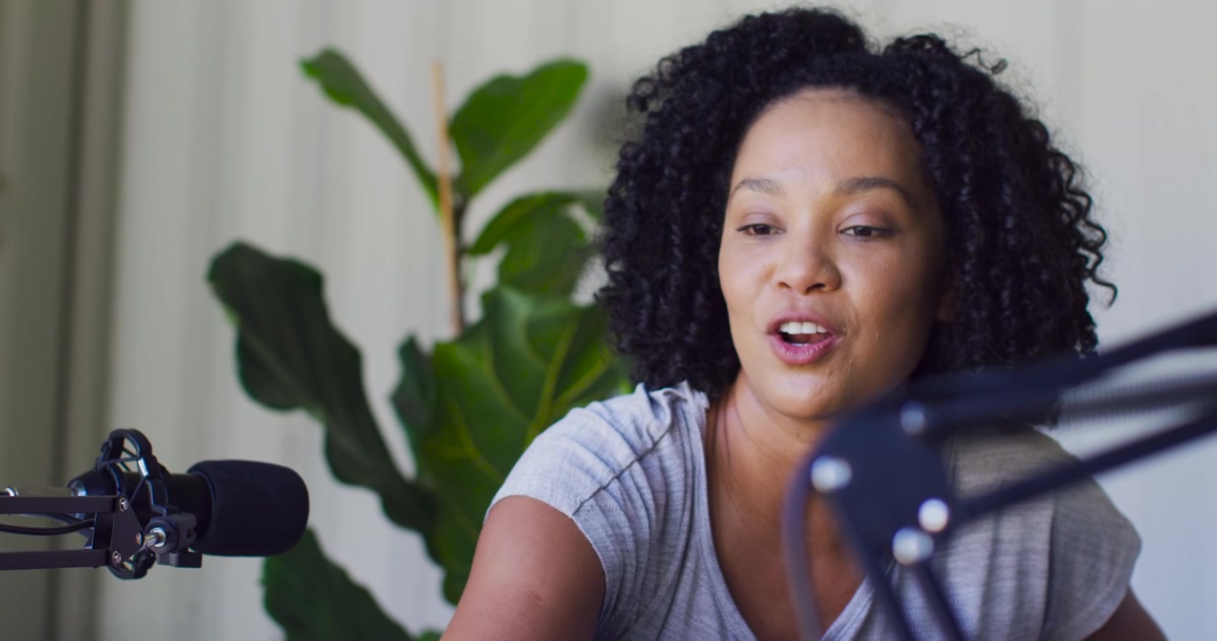 La telecamera si sposta verso l'alto su una donna afroamericana che si china usando il microfono del laptop, parlando mentre registra a casa.