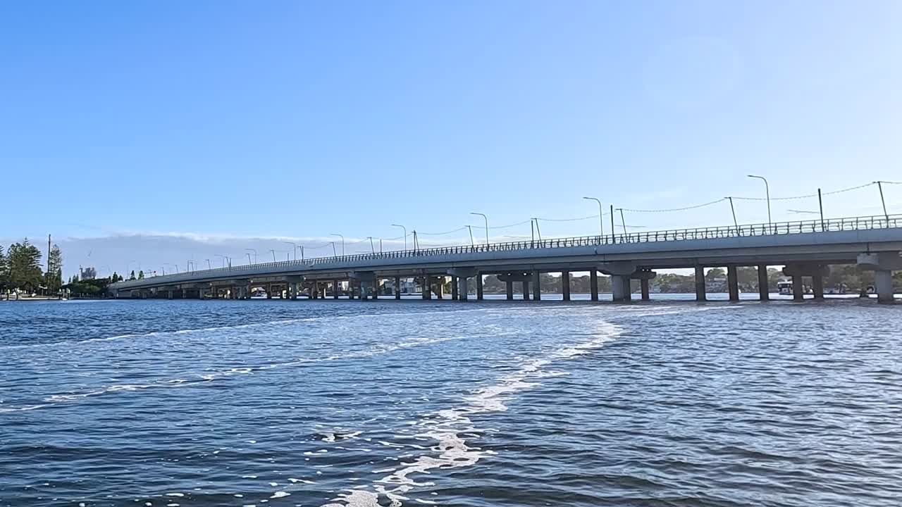A serene view of a bridge spanning across a tranquil river under a clear blue sky.