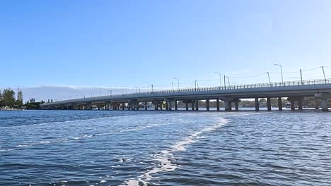 a serene view of a bridge spanning across a tranquil river under a clear blue sky.
