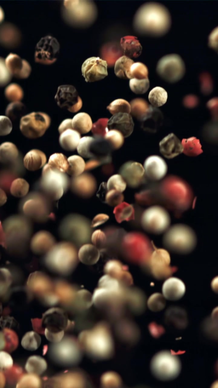 Mixed Peppercorns Falling in Slow Motion on a Dark Background