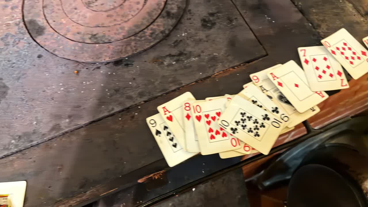 Hand collecting playing cards on stove top showing a combination of face and number cards