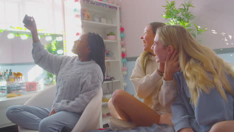 grupo de amigas adolescentes multiculturales sonrientes posando para una selfie en el teléfono móvil en casa