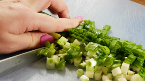 female cutting fresh spring onions on blue plastic board, close up view