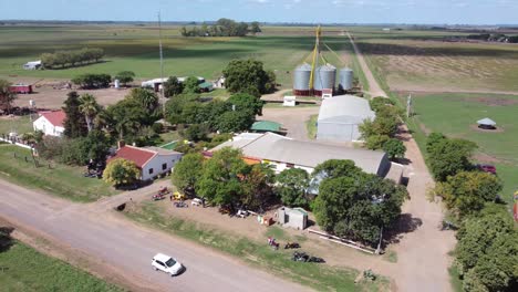 a drone captures an orbital aerial view of a sunny midday over a rural field in argentina, showcasing a house with visitors enjoying the serene countryside