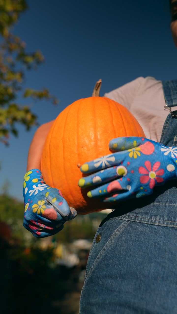 큰 오렌지색 호박을 들고 있는 사람