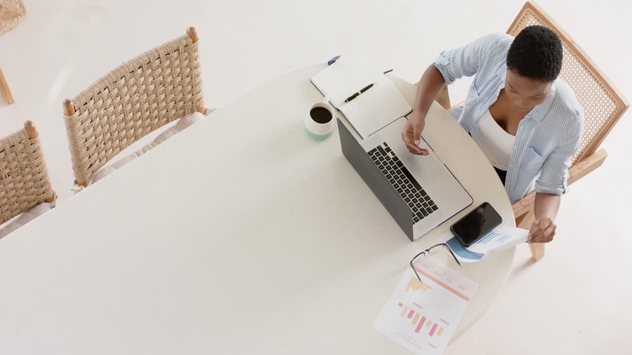 African american woman sitting at table using laptop for video call, slow motion