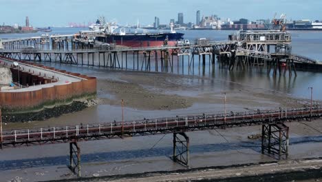 crude oil tanker ship loading at refinery harbour terminal pipeline aerial view dolly right