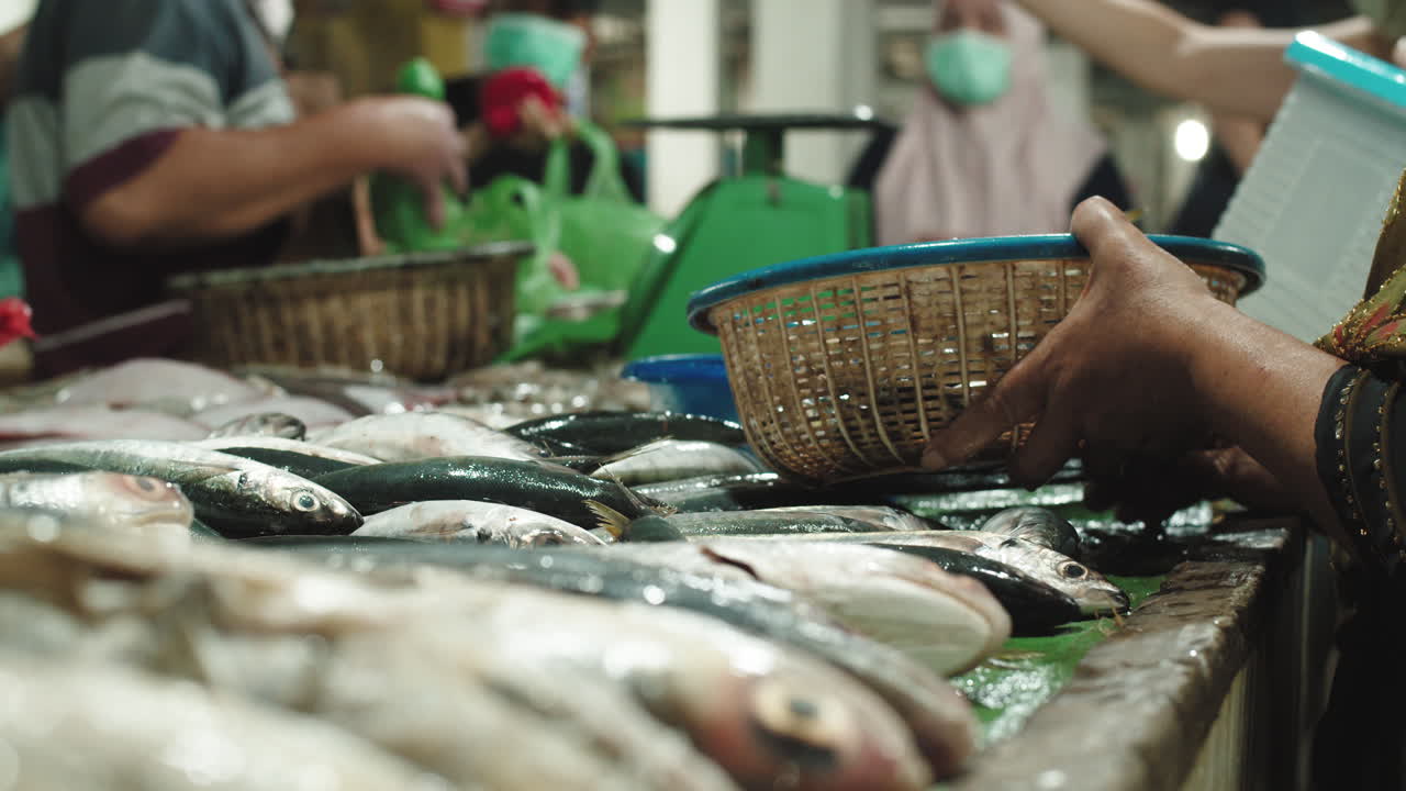 vendedores y clientes en un puesto de pescado en el mercado tradicional en medan, sumatra del norte, indonesia - primer plano extremo