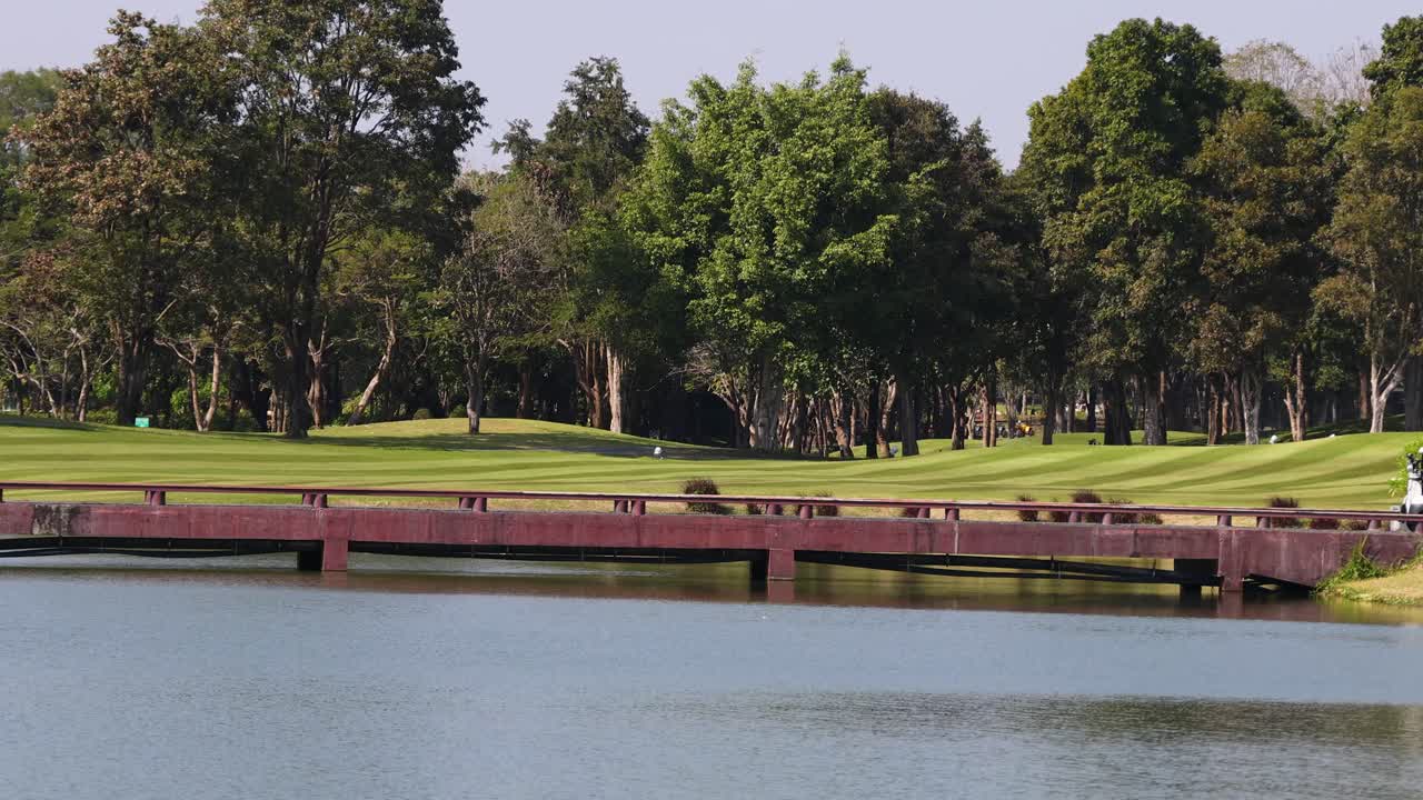 Plan large et fixe de voiturettes de golf traversant un pont au-dessus de l’eau à Khao Yai