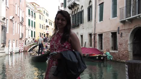 south asian woman traveler smiling at camera in the famous grand canal in venice, italy