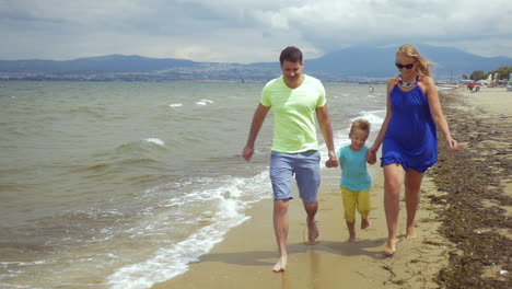 Familia-Descalza-De-Tres-Personas-Corriendo-Junto-Al-Mar