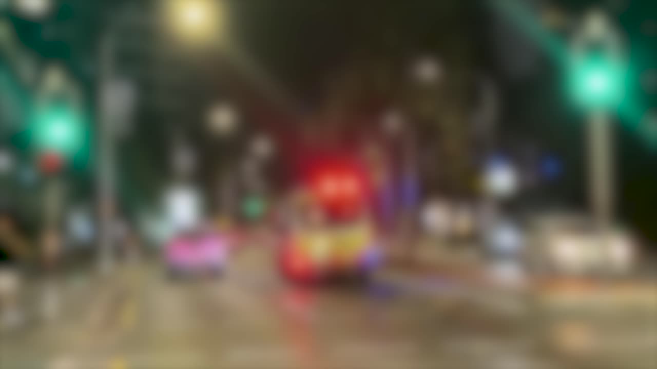 Un filmato fuori fuoco mostra un veicolo di emergenza con luci lampeggianti che guida nel traffico notturno