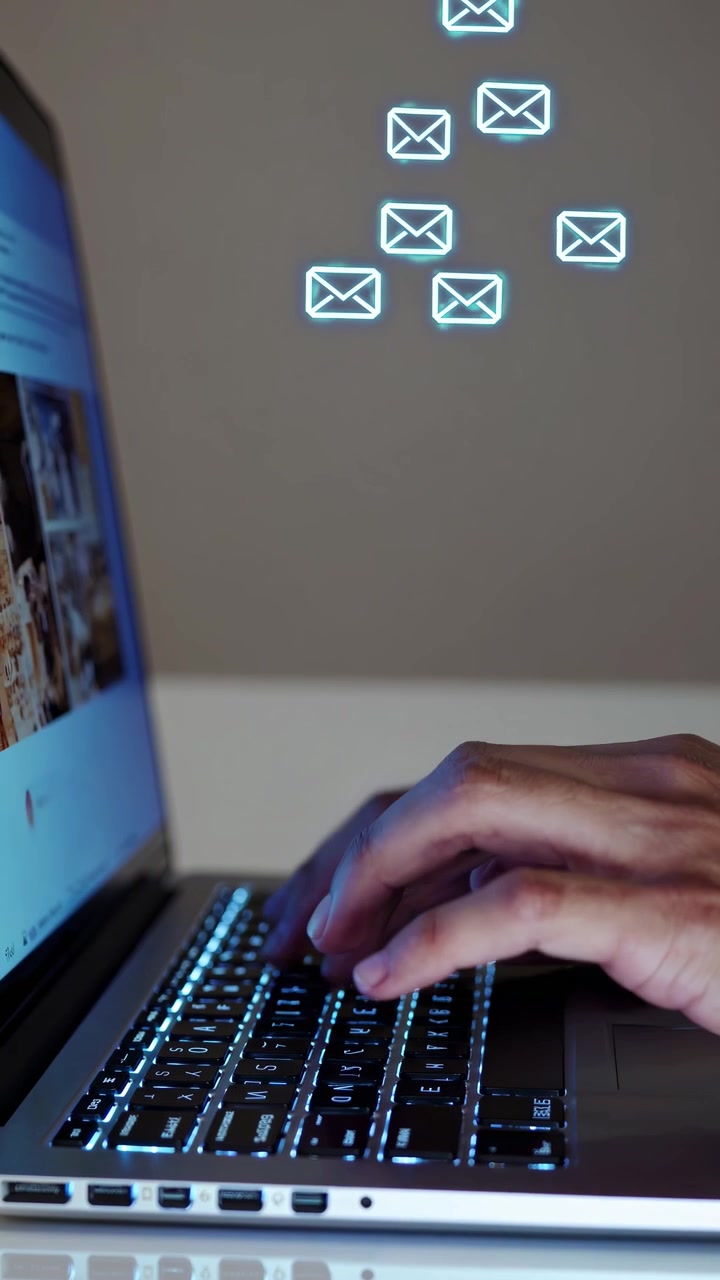 Close-up of Hands Typing on Laptop Keyboard with Email Icons