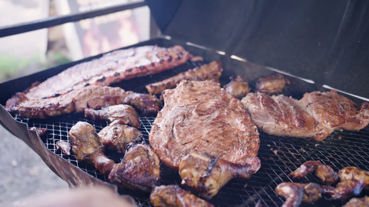 Primo piano di varie carni che cuociono su una griglia per barbecue all'aperto