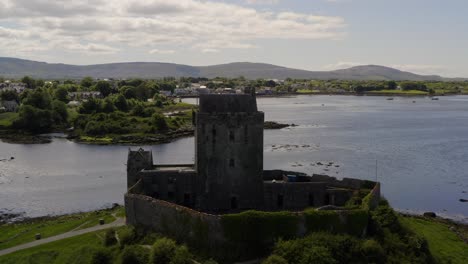 Dynamische-Luftaufnahme-Des-Kinvara-Tower-House,-Umgeben-Von-Seinem-Historischen-Schutzwall