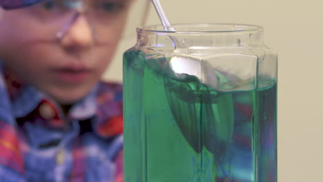 un niño pequeño mezclando colores en agua para un experimento científico