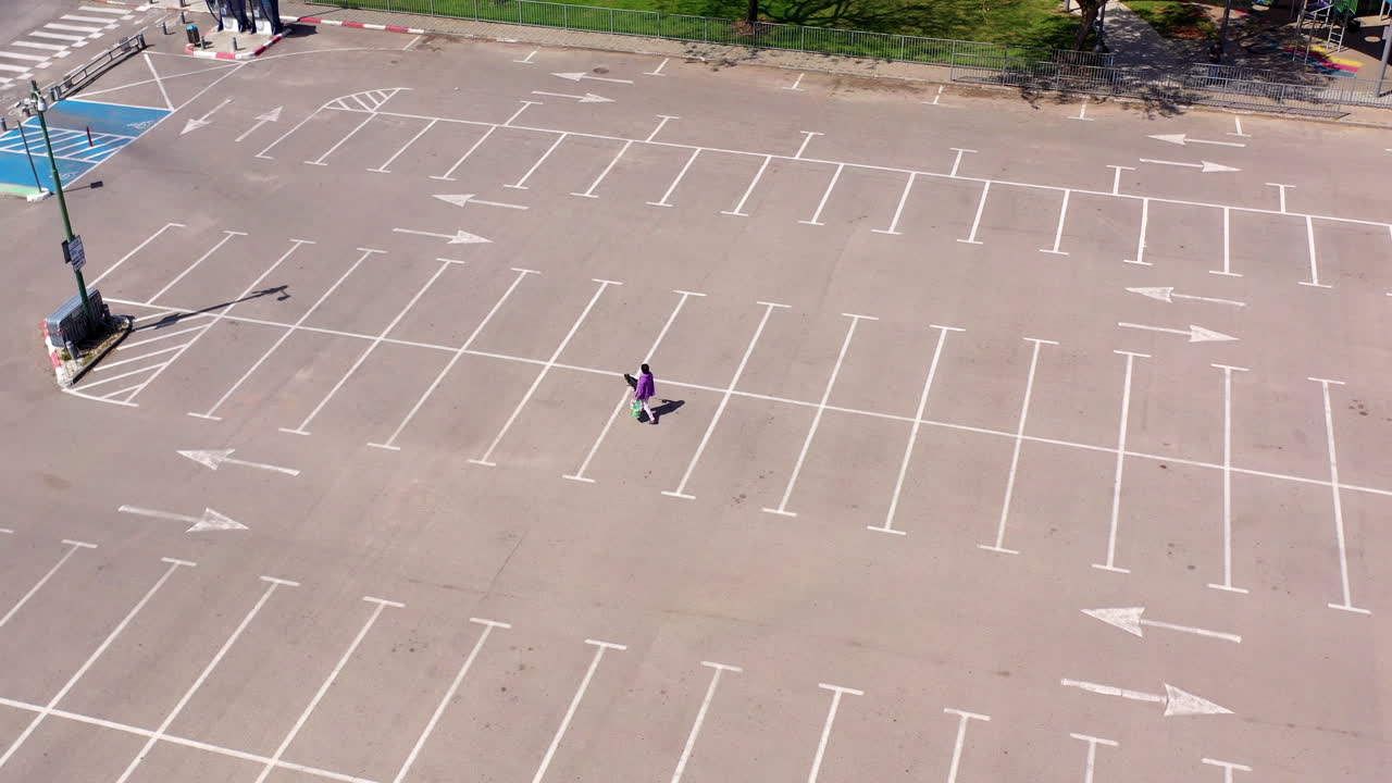 Lady with dog walking in Empty parking lot-Aerial
