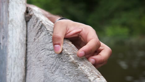 Close-up-of-hand-holding-wooden-boat,-travelling-up-the-Amazon-on-an-overcast-day