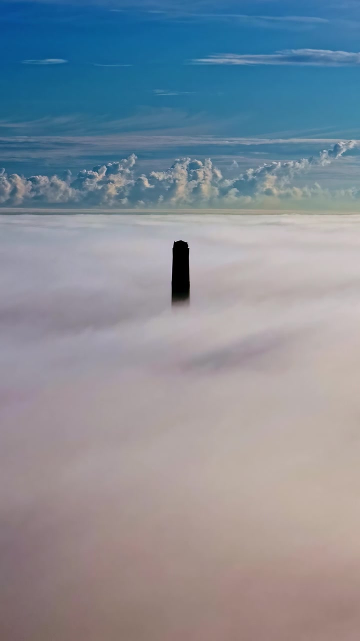 霧の日の出に雲の上にそびえ立つ煙突の空撮