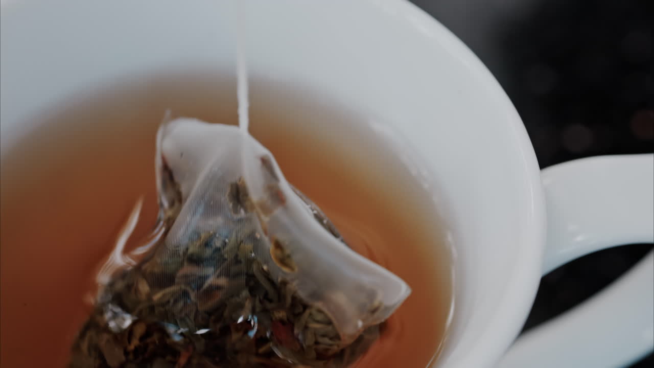 Close up of a green teabag in a white mug