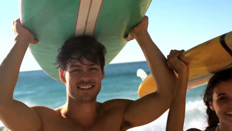 young couple carrying surfboard on their head