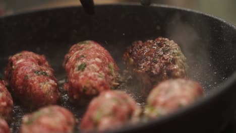 unrecognizable cook turning salisbury steaks on pan