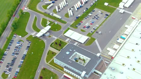 Aerial-top-down-view-of-the-big-logistics-park-with-warehouses,-loading-hub-and-a-lot-of-semi-trucks-with-cargo-trailers-awaiting-for-loading-unloading-goods-on-ramps