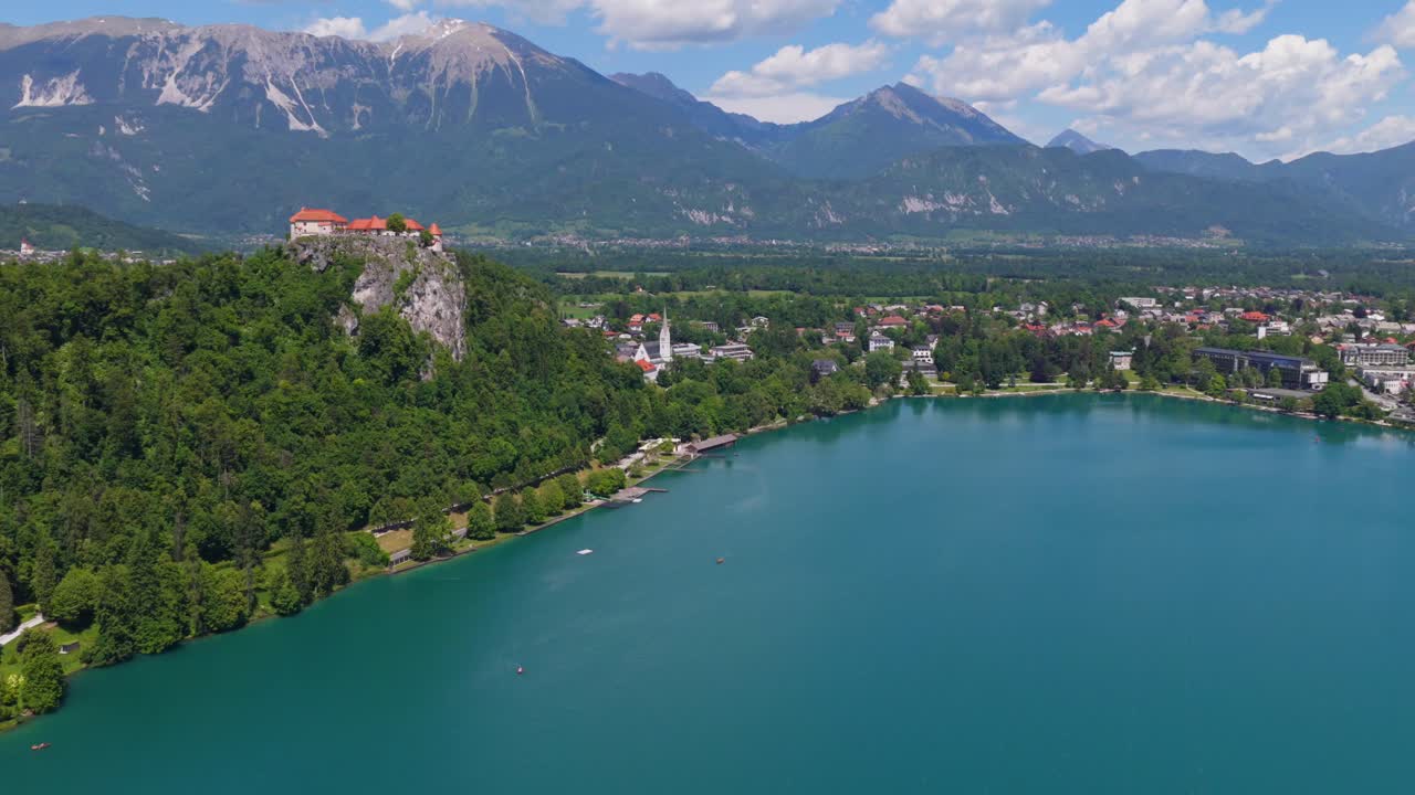 Ampia veduta aerea dell'intero bacino del Lago di Bled circondato da montagne alpine e foreste.