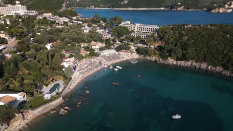 Vista-De-Pájaro-En-ángulo-Alto-Sobre-La-Bahía-Costera-De-Corfú,-Grecia,-Con-Filas-De-Sombrillas-En-La-Playa-Desde-El-Hotel