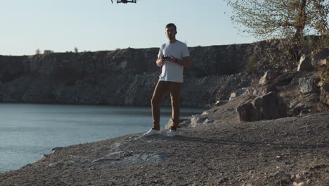 man controlling a drone by a lake