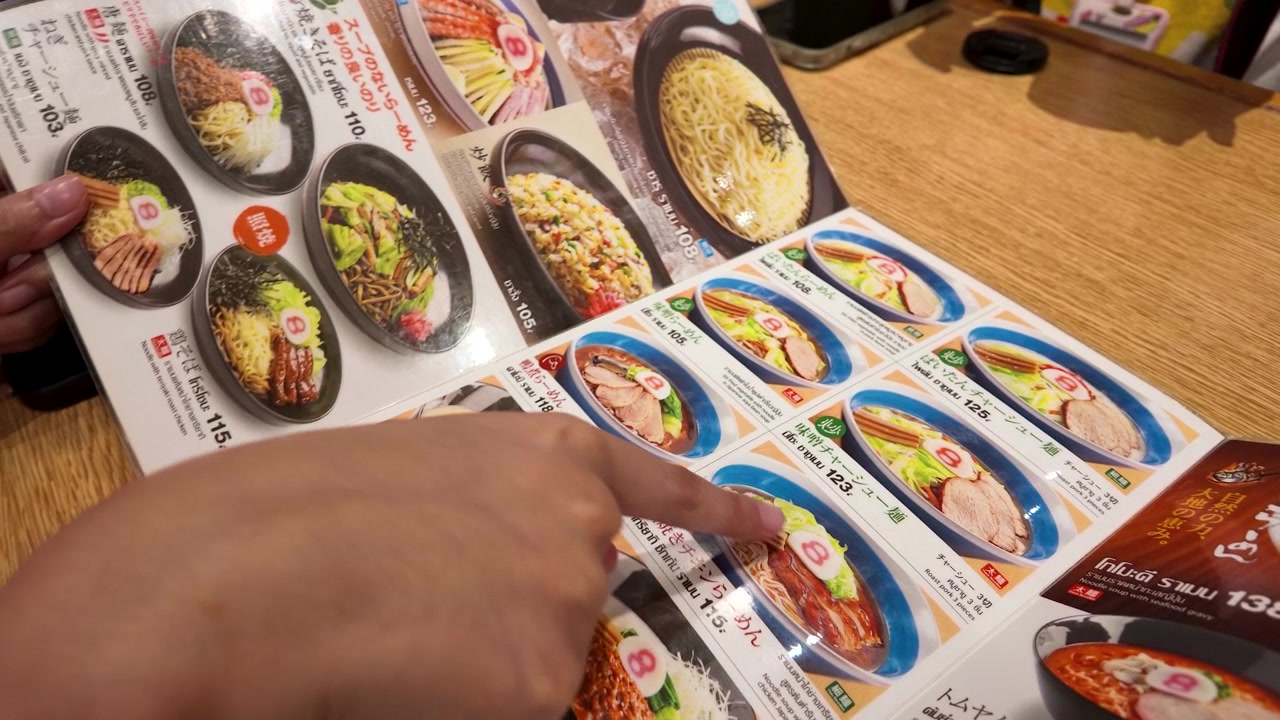Person peker på ramen-alternativer på en restaurantmeny