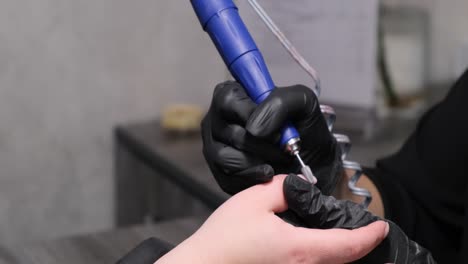 manicurist professionally cleans a client’s fingernails