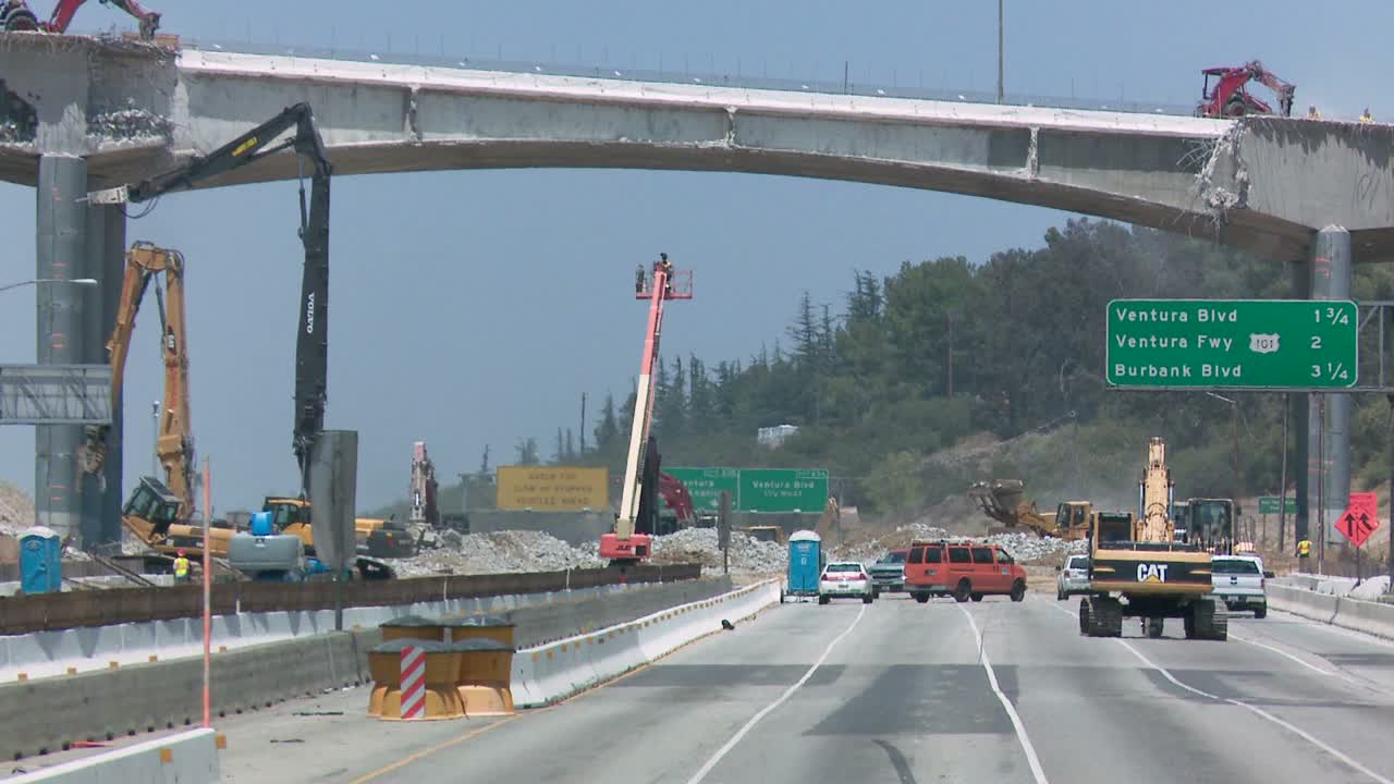 구경꾼 군중을 보여주기 위해 405번 고속도로의 폐쇄된 곳에서 작업 중인 승무원을 축소합니다.