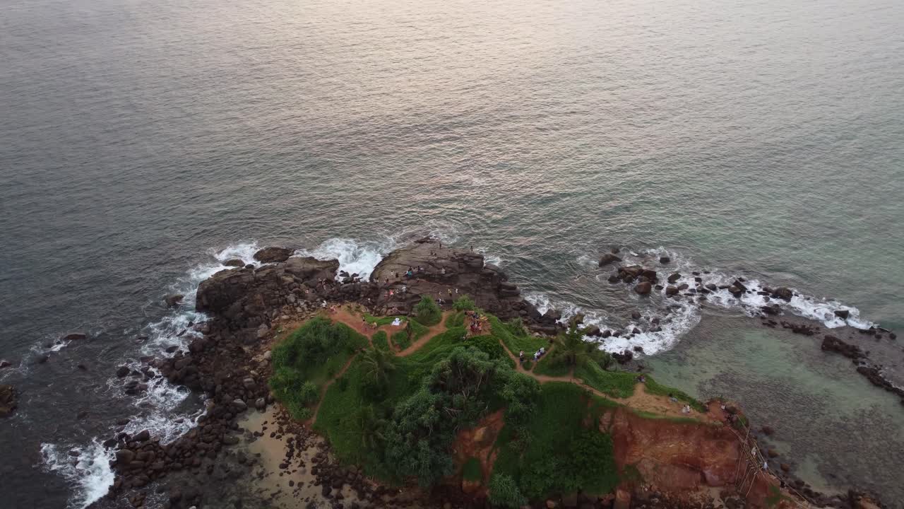 Drone aereo in panoramica su costa tropicale rocciosa, oceano e città a Mirissa Beach, destinazione turistica per le vacanze in Sri Lanka