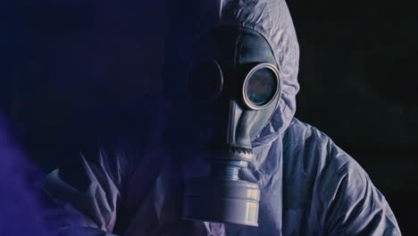 adult in white hazmat suit wearing face respirator surrounded by purple smoke