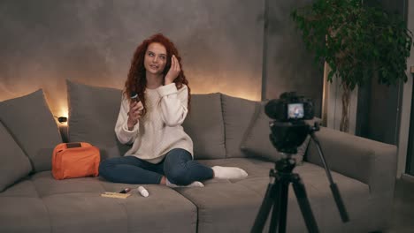 curly redhead young girl beauty vlogger is talking in front of camera recording video for online blog in internet