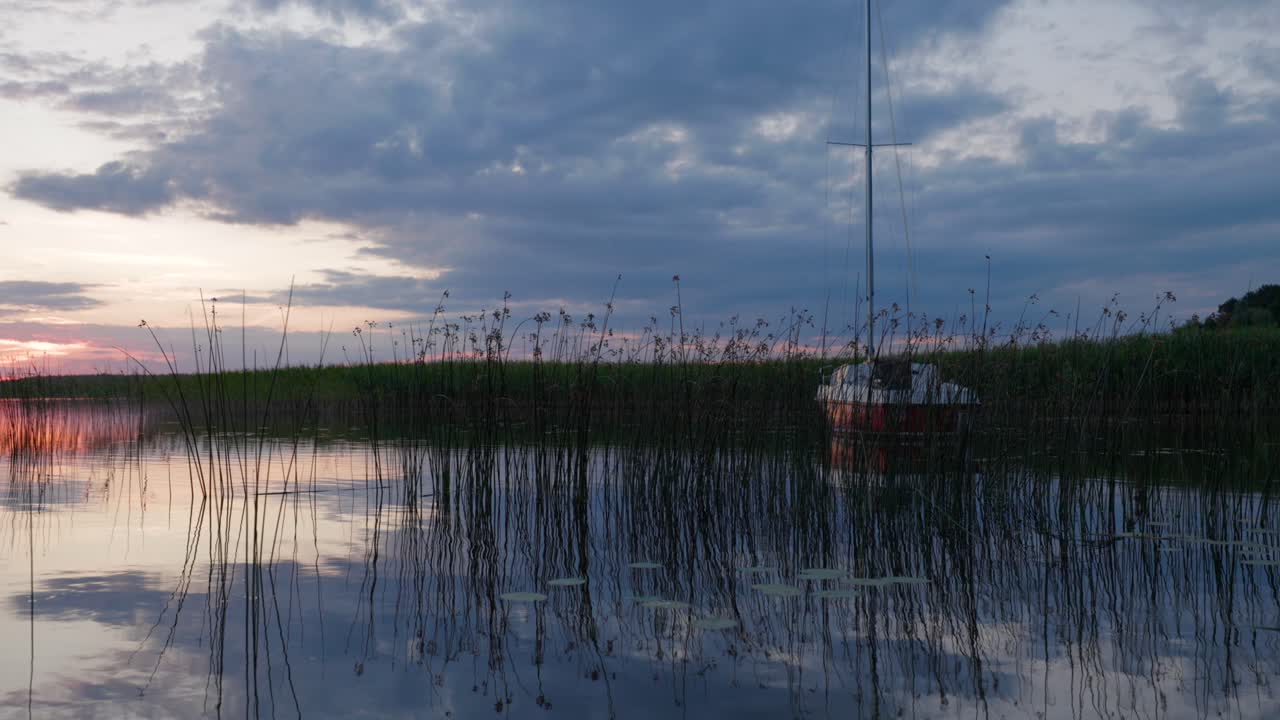 A charming corner of the river with a sailboat at anchor, illuminated by the setting sun