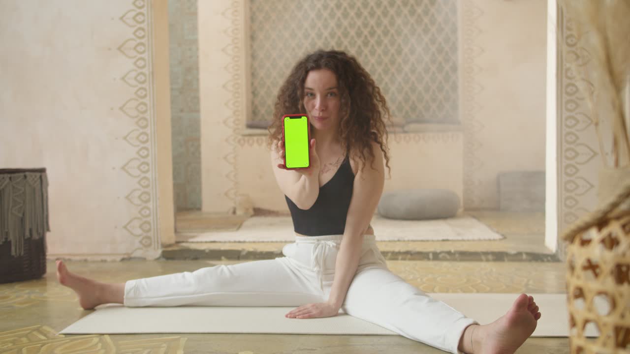 entrenadora de fitness de cabello rizado que muestra ejercicios en línea usando un teléfono inteligente con pantalla verde. aprendizaje y estudio en línea, estilo de vida activo y saludable entrenamiento deportivo femenino entrenamiento bienestar y ejercicio en interiores