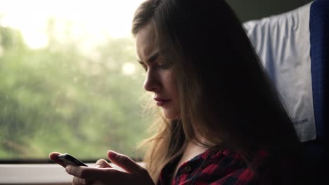 imágenes cercanas de una chica caucásica de cabello largo viajando en un tren. sentada y hablando en el teléfono móvil. concentrada y tranquila. vista lateral