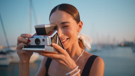 woman taking a photo with a vintage camera at a harbor