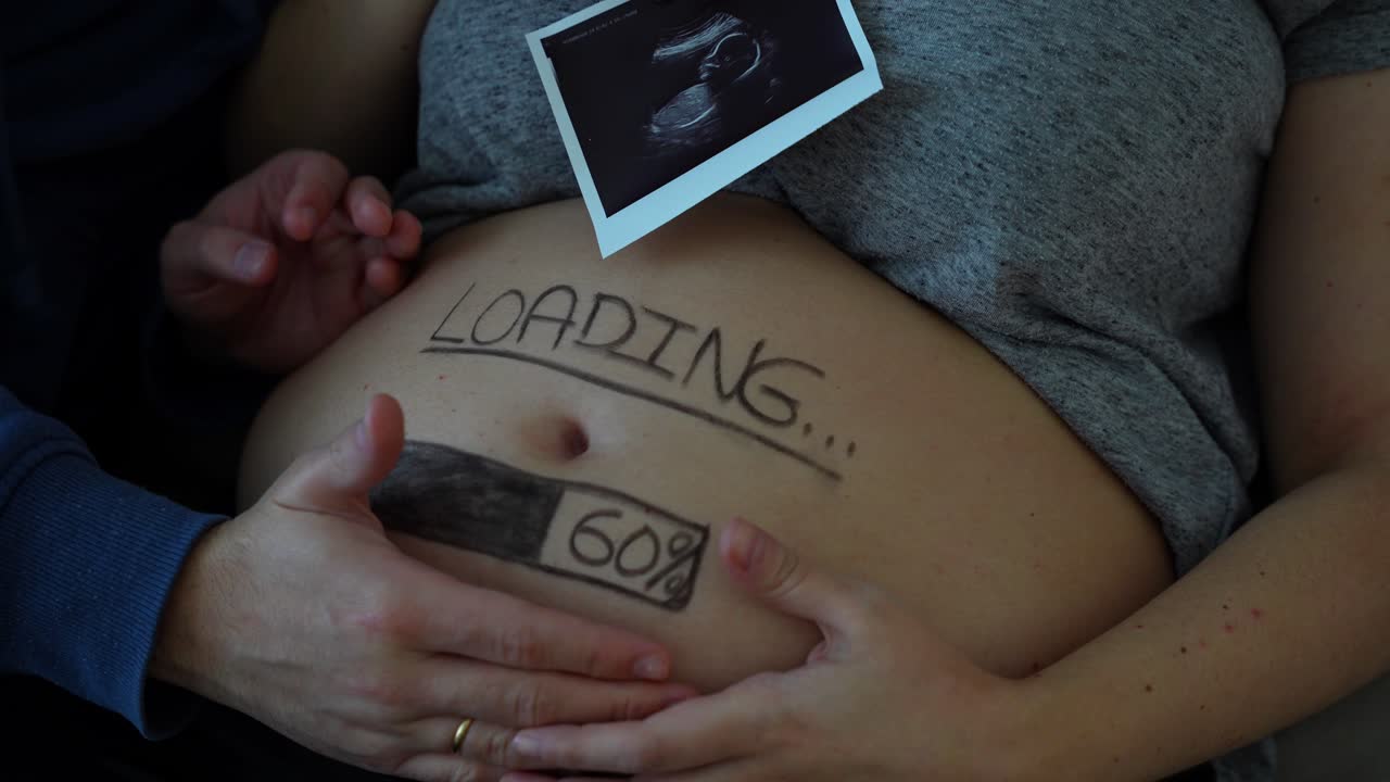 el marido toca el vientre de la esposa embarazada con una barra de carga y una foto de ultrasonido