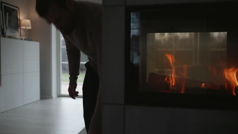 scandinavian home interior, person adds logs to fireplace,nordic lifestyle