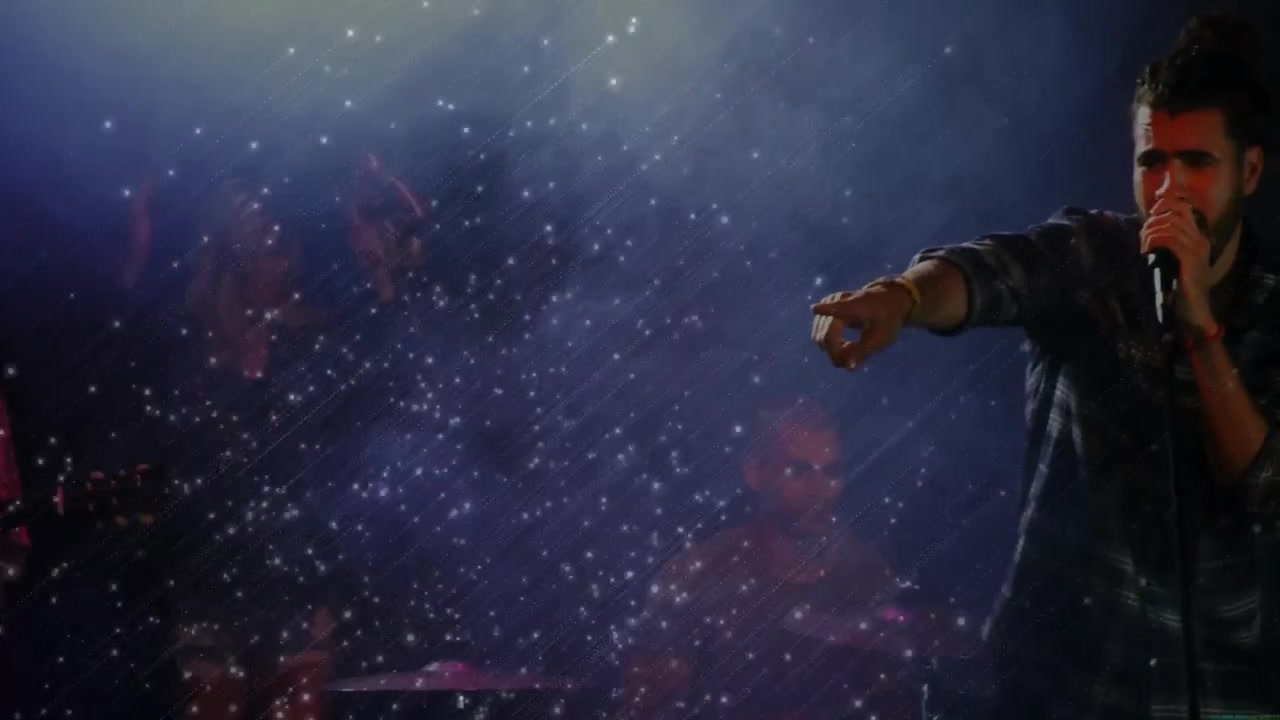 Lead vocalist entering from right moving inward grabbing mic, singing live music through confetti