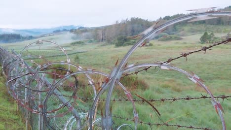 Razor-wire-fence-barrier-separates-beautiful-landscape-and-dirt-path