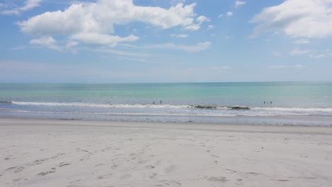 Strand-Und-Meer-Mit-Menschen,-Die-Im-Wasser-Schwimmen