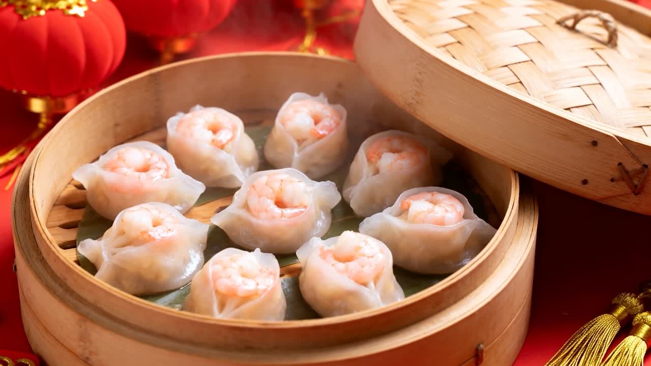 Menghasilkan uap, alat pengukus berisi sembilan dumpling udang di atas kain merah untuk disajikan dengan rumbai emas