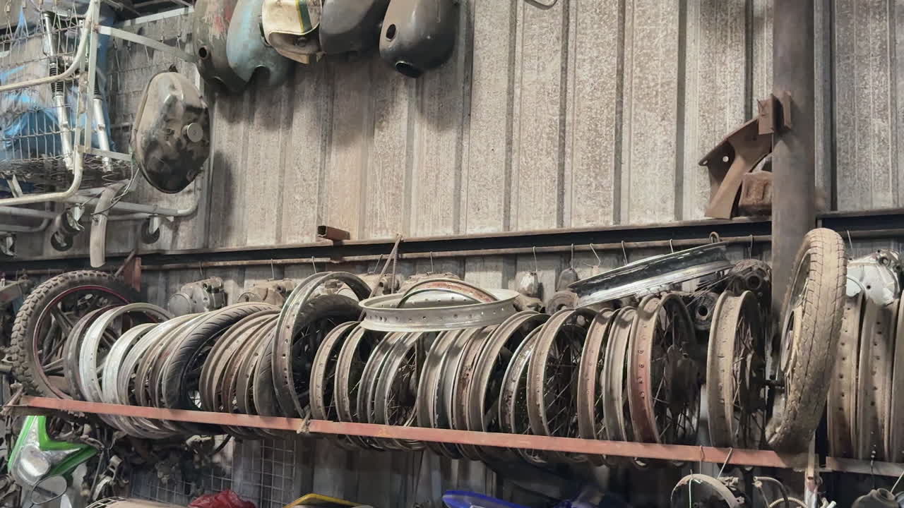 Pan right shot showing old motorbike rims and parts neatly stored at Phung Motorbike Sister workshop Ha Noi.