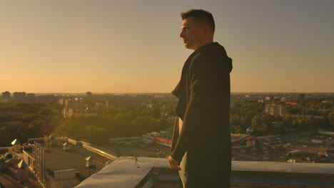 Hacker-using-laptop-on-rooftop-with-city-view-and-forex-chart.-Hacking-and-stats-concept.-A-man-at-sunset-in-slow-motion-writing-software-code-on-a-laptop