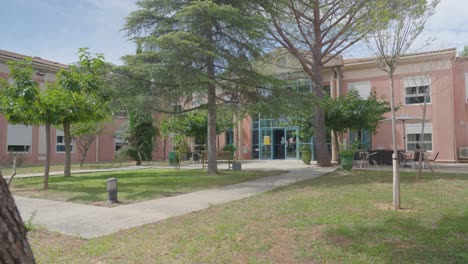 pan to the right of the nursing home entrance reveals a beautifully manicured green garden