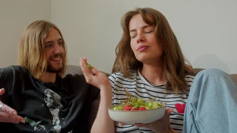 couple enjoying fruit snack on the sofa